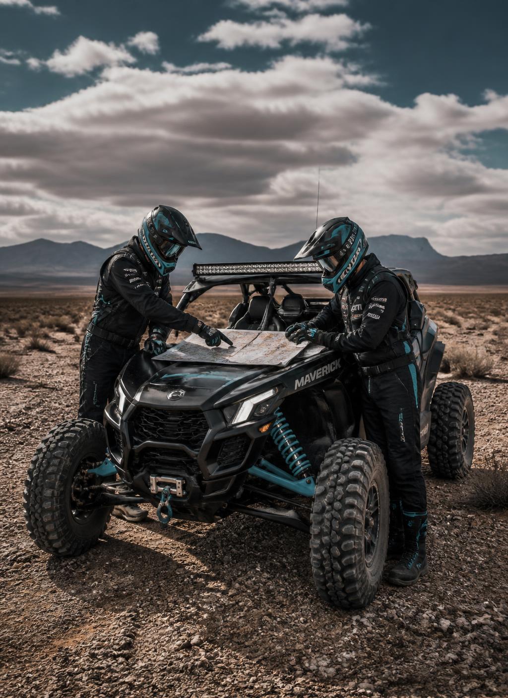 Two expedition drivers studying a map on a Maverick hood in the desert